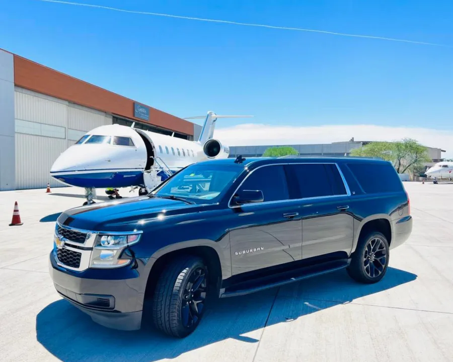 Black Chevrolet Suburban with a private jet in the background